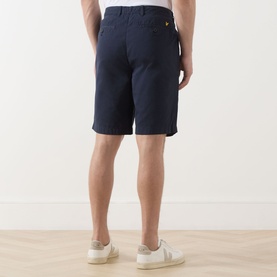 Model wearing Lyle & Scott Eagle Logo Chino Shorts in Dark Navy, rear view, styled with white trainers.