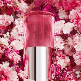 Dior Miss Dior Parfum Mini Miss Solid Perfume in pink translucent case with silver base, styled against a pink floral backdrop