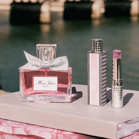 Dior Miss Dior Parfum Mini Miss Solid Perfume set with pink bow-adorned bottle and houndstooth-cased solid perfume stick, outdoor setting