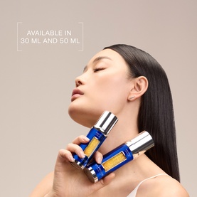 Model with La Prairie Skin Caviar Liquid Lift serum in blue bottle held to neck, available in 30ml and 50ml sizes