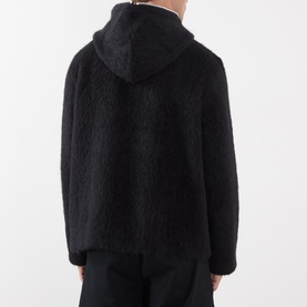 Model wearing Our Legacy Black Zip Through hoodie, rear view, textured shearling-effect knit in black with matching black trousers.