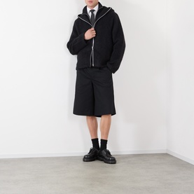 Model wearing Our Legacy Black Zip Through knit hoodie, styled with black shorts, tie and chunky leather shoes.