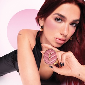Model with YSL Make Me Blush Bold Blurring Blush in Rose Haze 6, compact held up to face, wearing gold hoop earrings and black top