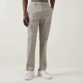 Model wearing Calvin Klein Stretch Slim-Leg Chinos in Vintage Khaki, slim mid-rise fit with tonal stitching, styled with white trainers.