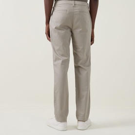 Model wearing Calvin Klein Stretch Slim-Leg Chinos in Vintage Khaki, slim-fit with clean hems, styled with white trainers. Rear view.