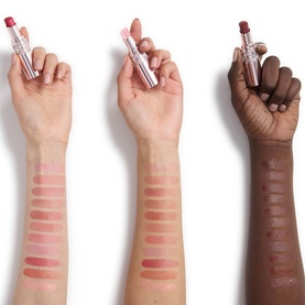 Three arms showing YSL Loveshine Plumping Lip Oil Gloss swatches across skin tones, each holding a lipstick, with 1 Thunder Stealer among shades shown