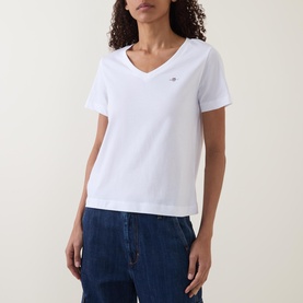 Model wearing Gant Shield Logo T-shirt in white, V-neckline with embroidered logo, styled with blue denim jeans