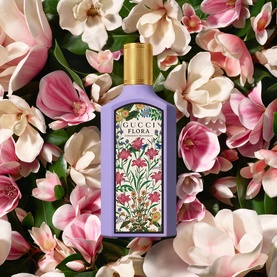Gucci Flora Gorgeous Magnolia Eau de Parfum in lilac bottle with gold cap, surrounded by fresh pink and white magnolia blooms