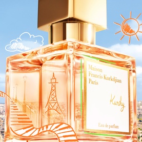 Maison Francis Kurkdjian Kurky Eau de Parfum in a faceted orange glass bottle with gold cap against a bright blue sky backdrop