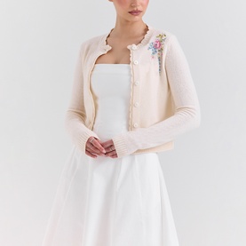 Model wearing House of CB Anjou Knitted Cardigan in Cream Floral with scallop edges, floral embroidery, and button-down front, styled over a white