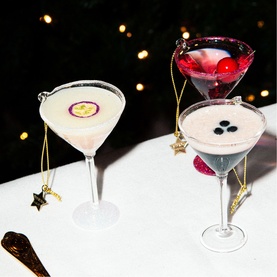 Vondels Cosmopolitan Cocktail Glass Tree Decoration in pink, styled with two other cocktail glass ornaments, gold star nameplates