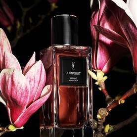 YSL Le Vestiaire des Parfums Jumpsuit EDP in dark amber bottle with black cap, styled with deep pink magnolia flowers