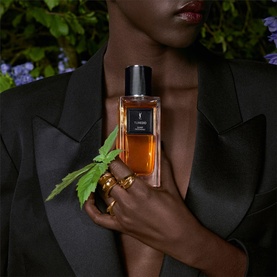 Model with YSL Le Vestiaire des Parfums Tuxedo Eau de Parfum, amber glass bottle with black cap, styled with gold rings and black blazer.