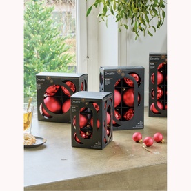 Kaemingk Round Glass Tree Decoration Six-Piece Set in red, three boxed sets displayed on a marble surface near a window