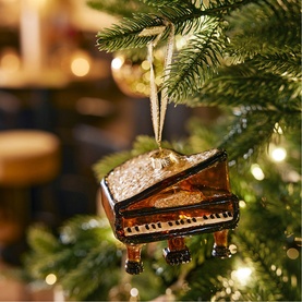 Kaemingk Grand Piano Glass Tree Decoration in brown with glitter embellishment, hanging on a lit Christmas tree