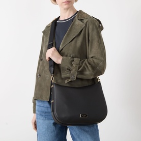 Model carrying Kate Spade Liv Large Hobo Bag in black pebbled leather with gold-tone hardware and adjustable strap, styled with olive suede jacket