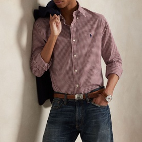 Model wearing Ralph Lauren Gingham Check Stretch Shirt in wine, small check pattern, long sleeves. Styled with dark jeans and a brown belt
