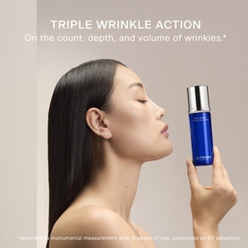 Model with LA PRAIRIE Skin Caviar Hydro Emulsion Moisturiser 30ml, holding the blue and silver bottle beside her face