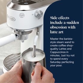 De'Longhi espresso machine with steam wand frothing milk in a stainless steel jug, styled in white and silver