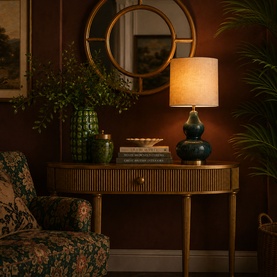 Mindy Browne Astor Table Lamp in blue ceramic with gourd silhouette and linen shade, styled on a gold console table with mirror and plants