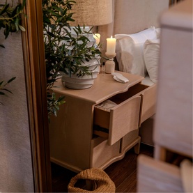 Mindy Browne Louis Large Mirror in gold, lifestyle shot showing reflection of styled bedroom with nightstand, lamp, candle and plant
