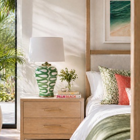 Mindy Browne Julie Patterned Table Lamp in white and green ceramic, styled on a wooden bedside table in a bright bedroom setting.