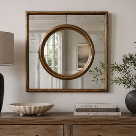 Square antiqued wall mirror with gold-toned frame and circular centre mirror, styled on a wooden sideboard with books and decorative bowl