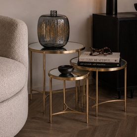 Mindy Browne Brookville Round Mirror Three-Piece Table Set in gold with iron frames and mirrored tops, styled with vase and books in a living room