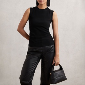 Model wearing Reiss black sleeveless ribbed top with leather wide-leg trousers, carrying a small black structured handbag.