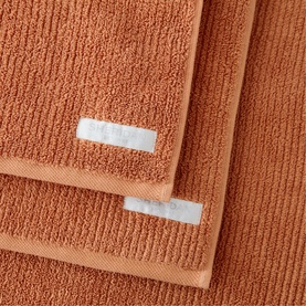Sheridan Living Textures Towel Maple in orange, 100% cotton terry fabric, shown folded with branded labels visible