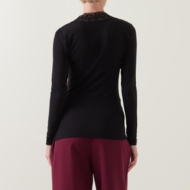 Model wearing Masai Dionius Lace Trim Top in black with lace collar detail, long sleeves, paired with burgundy trousers. Back view