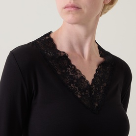 Model wearing Masai Dionius Lace Trim Top in black, close-up showing V-neckline with delicate floral lace trim detail