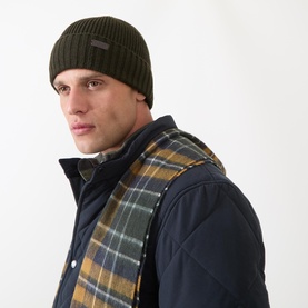Model with Barbour Carlton Solid Beanie Hat in olive, rib knit with turned-up brim, styled with plaid scarf and navy quilted jacket