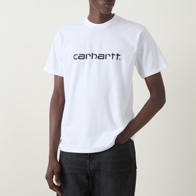 Model wearing Carhartt Script Logo T-Shirt in white with black logo lettering, crew neck, short sleeves, styled with dark trousers.
