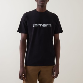 Model wearing Carhartt Script Logo T-Shirt in black with white logo lettering. Styled with tan shorts.