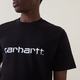 Model wearing Carhartt Script Logo T-Shirt in black with white logo lettering across chest, crew neckline, short sleeves