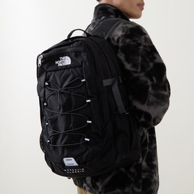 Model carrying North Face Borealis Classic Backpack in black, with bungee cord front detail and padded straps, styled with grey camo jacket