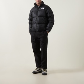 Model wearing North Face black nylon puffer jacket with stand collar, styled with black trousers and chunky trainers