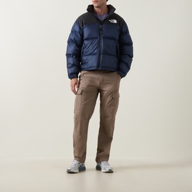 Model wearing North Face 1996 Retro Nuptse Down Jacket in Navy/Black, styled with tan cargo trousers and white trainers