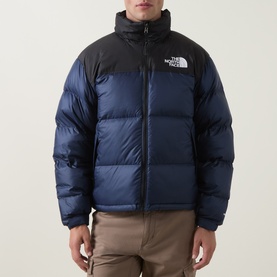 Model wearing North Face 1996 Retro Nuptse Down Jacket in Navy/Black, quilted puffer silhouette with stand collar and logo chest print