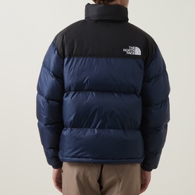 Model wearing North Face 1996 Retro Nuptse Down Jacket in Navy/Black, rear view showing quilted panels, black yoke, and logo print.