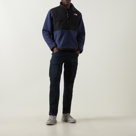 Model wearing North Face Retro Denali Fleece Sweatshirt in Summit Navy/Black with zip chest pockets, styled with dark cargo trousers and grey