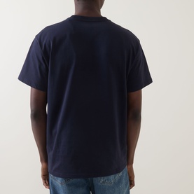 Model wearing Carhartt Chase Logo T-Shirt in navy, rear view showing dropped shoulders, straight hem and short sleeves, styled with blue jeans.