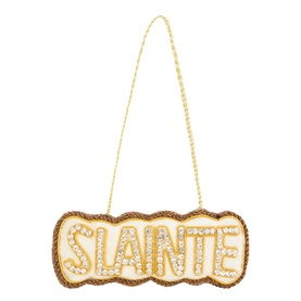 Cream and gold beaded hanging decoration with "SL&Aacute;INTE" text in diamant&eacute; lettering, scalloped border, and gold chain hanger.