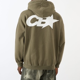 Model wearing Cole Buxton Star Racing Hoodie in khaki, back view showing large CB star logo print, paired with distressed jeans