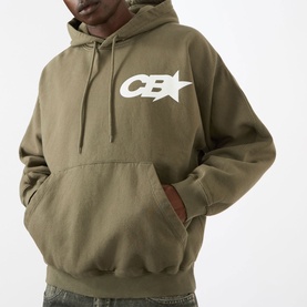 Model wearing Cole Buxton Star Racing Hoodie in khaki with contrast white CB star logo on chest and kangaroo pocket