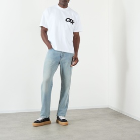 Model wearing Cole Buxton white cotton T-shirt with chest logo graphic, styled with light wash jeans and black platform trainers.