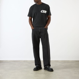 Model wearing Cole Buxton T-Shirt in Vintage Black with white chest logo, styled with wide-leg black jeans and black chunky shoes.