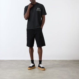 Model wearing Cole Buxton Sportswear Letter Logo T-Shirt in Vintage Black with matching black shorts, black socks and white gum-sole trainers.