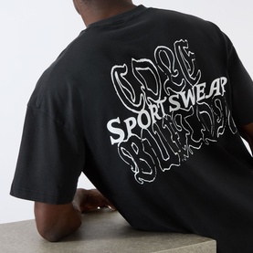 Model wearing Cole Buxton Sportswear Letter Logo T-Shirt in Vintage Black, back view showing bold white graphic logo print.